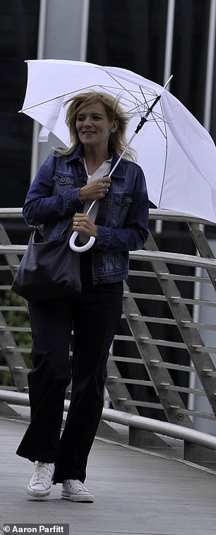 Chilly: The actress, 41, who plays Leanne Battersby, shielded herself with a large white umbrella as she took a break from filming
